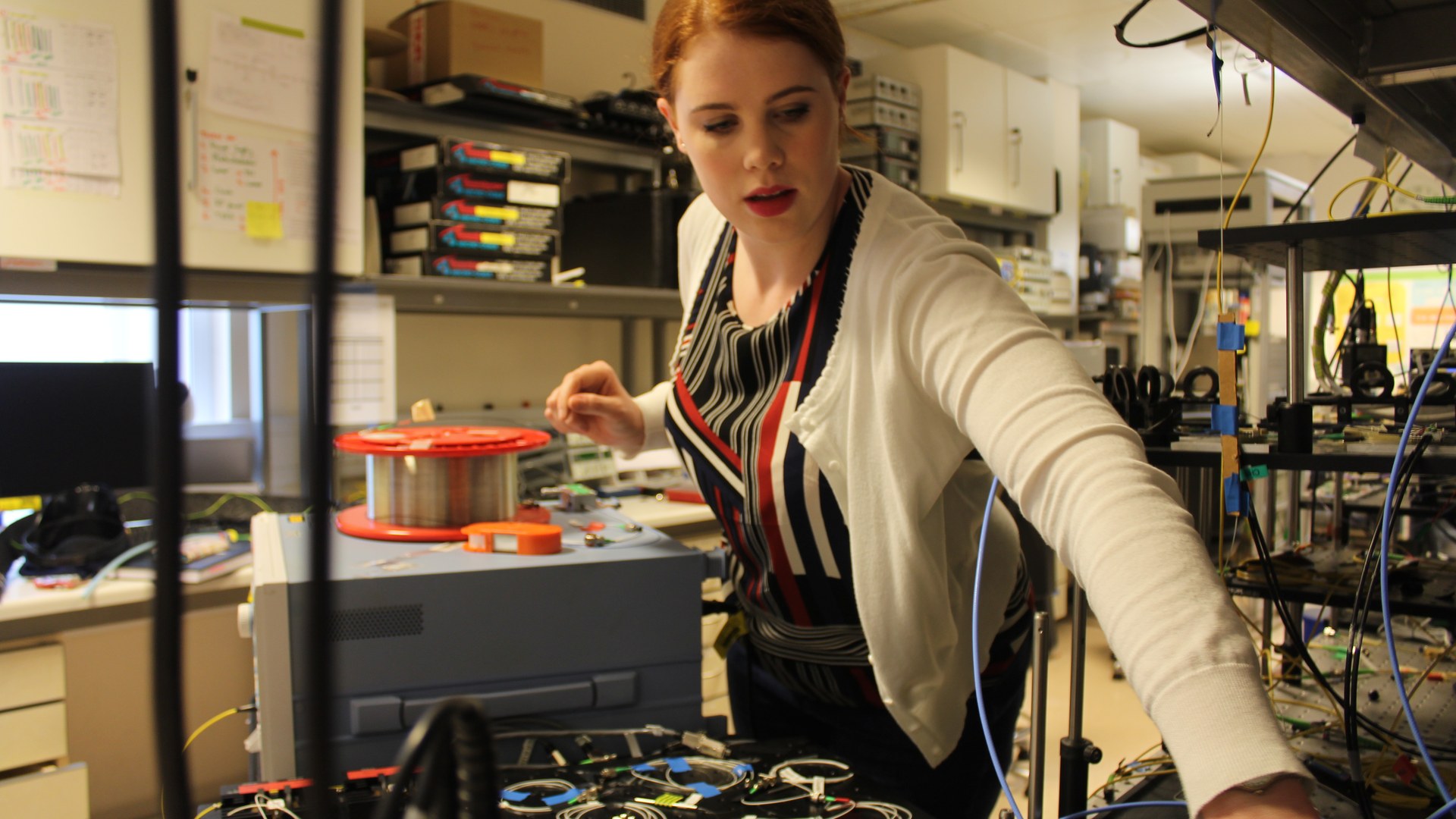 An engineer adjusts an instrumented optical-fibre testbed - the optical-interconnect layer of the AI data centre, where Marvell's 1.6T modules, PAM4 DSPs and silicon photonics do their work. Photo: NiamhTalking90 / Wikimedia Commons, CC BY-SA 4.0